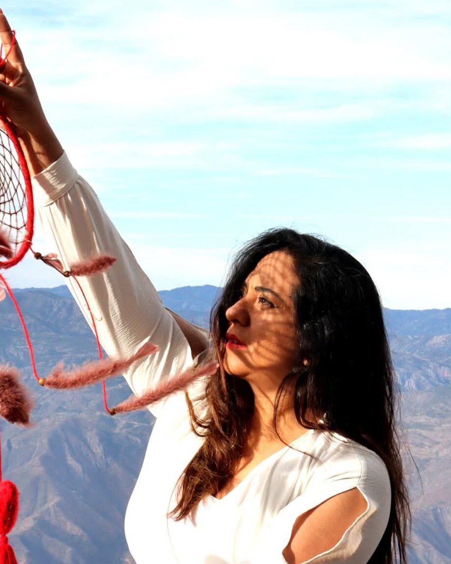 Victoria Arce sostiene un atrapasueños rojo frente a un paisaje de montaña